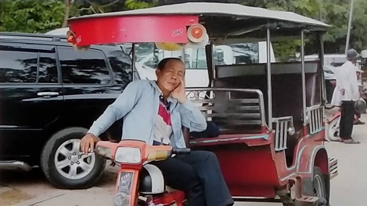 Taxista, descansant amb una mà al manillar, al Vietnam. Eva Murgui