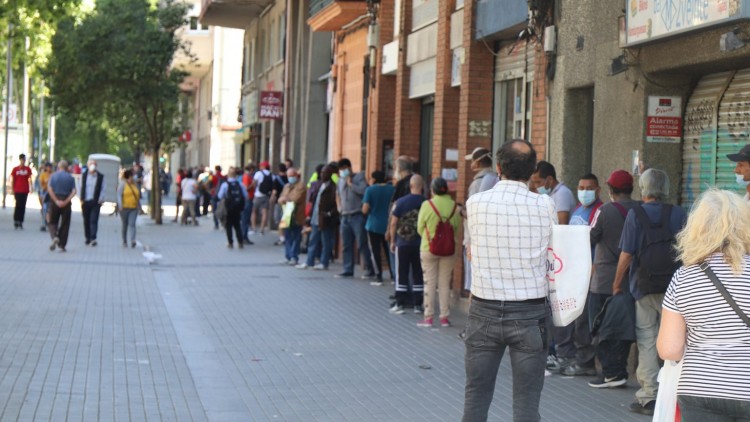 Persones necessitades fan cua per rebre aliments