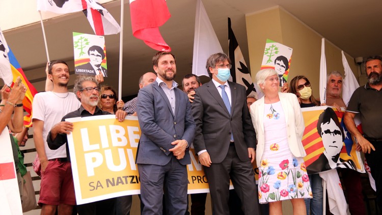 Puigdemont, Comín i Ponsatí a la sortida del tribunal de Sàsser i davant una pancarta de suport, el 4 d'octubre del 2021. Agència Catalana de Notícies
