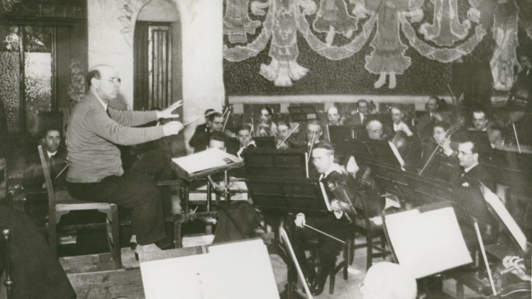 Pau Casals davant la seva orquestra durant un assaig al Palau de la Música Catalana. ©Centre de Documentació de l’Orfeó Català (CEDOC)